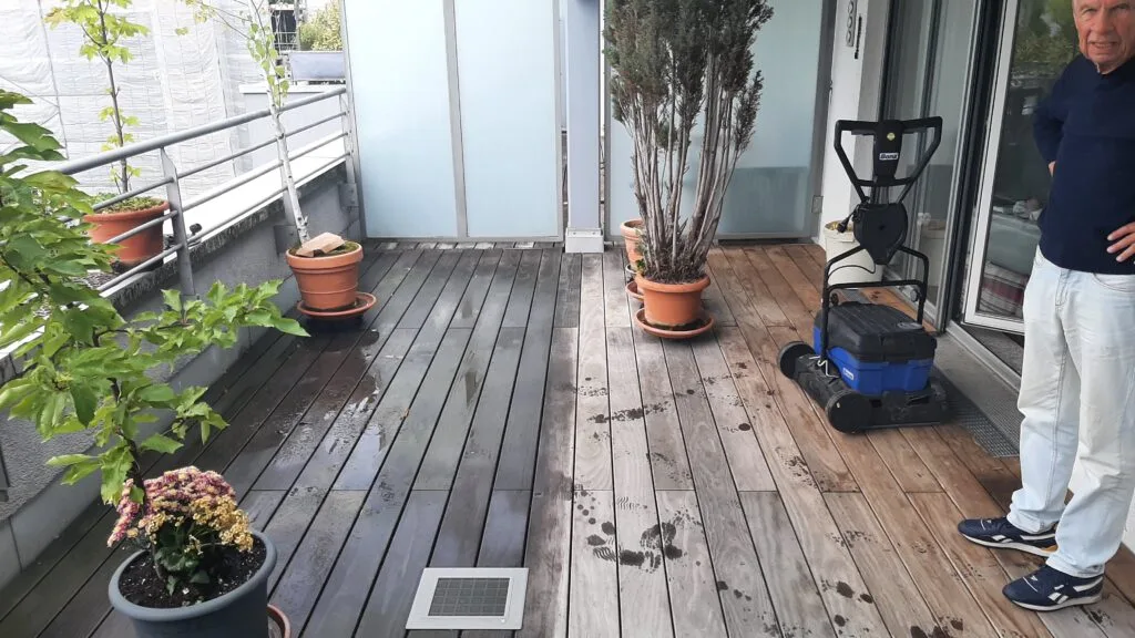 Holzterrasse mit Reinigungsmaschine und unterschiedlich gereinigten Dielen